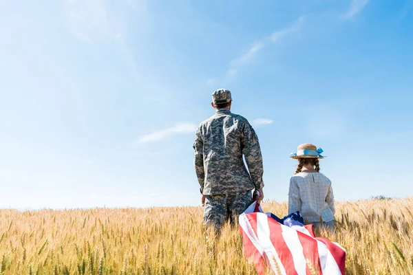 制服を着た兵士と子供が野原に立ち アメリカ国旗を掲げる背中の眺め — ストック写真