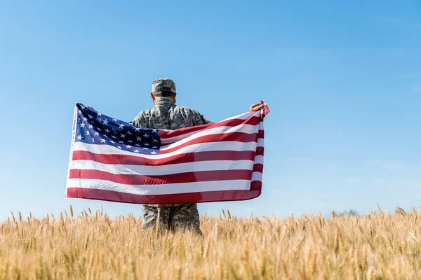 Visão Traseira Homem Boné Uniforme Militar Segurando Bandeira Americana Campo — Fotografia de Stock
