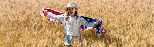 panoramic shot of cute and happy kid holding american flag in field 