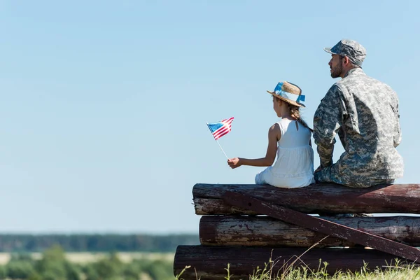 Patriotiske Barn Som Holder Amerikansk Flagg Nær Veteranfar Mens Sitter – stockfoto