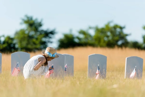 Niedliches Kind Sitzt Neben Grabstein Mit Amerikanischer Flagge Auf Friedhof — Stockfoto