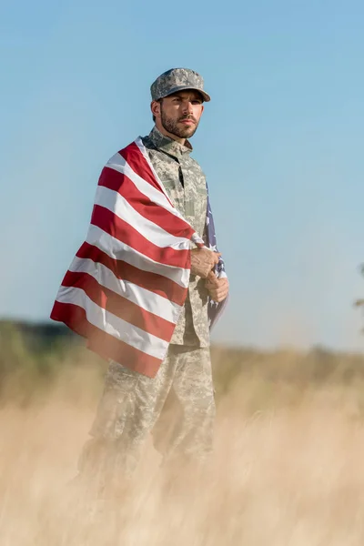 Selektywny Fokus Człowieka Mundurze Kamuflażu Cap Posiadania Amerykańskiej Flagi Złotym — Zdjęcie stockowe
