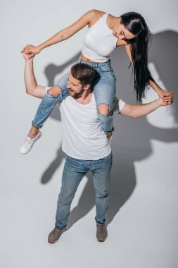 gülümseyen ve el tutarak omuzlarında kız arkadaşı tutan genç adam yüksek açı görünümü