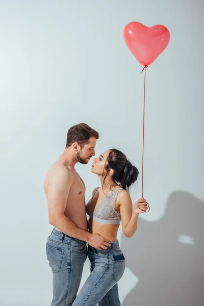セクシーなカップルが抱きしめ ハートの形で風船を持っている女の子ながらキスをしようとする — ストック写真