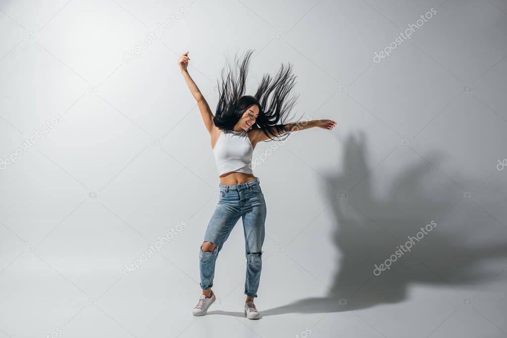 full length view of girl dancing with hands in air on white background 