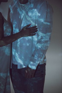cropped view of two people standing in darkness and hugging each other  clipart