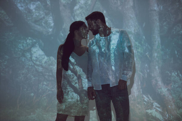 two people standing in darkness and holding hands