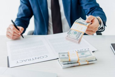 cropped view of man holding money while signing contract  clipart