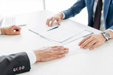 Masa üzerinde sözleşme ve kalem yakınında işadamlarının kırpılmış görünümü 