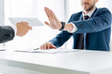 cropped view of man gesturing near business partner giving envelope with bribe in office  clipart