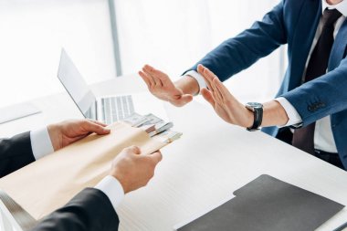 cropped view of man gesturing near business partner giving envelope with bribe  clipart