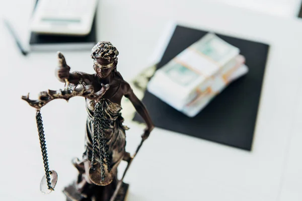 选择性的焦点正义的雕像接近现金在办公室表 — 图库照片