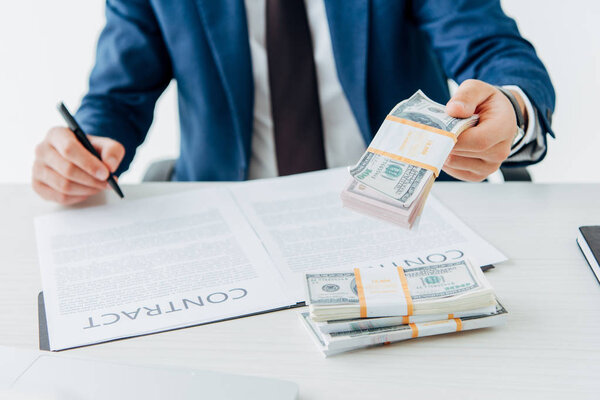 cropped view of man holding money while signing contract 