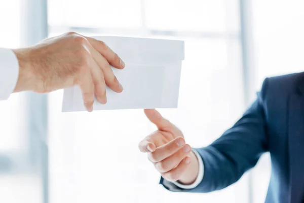 オフィスのビジネスパートナーに賄賂で白い封筒を与えるビジネスマンのトリミングされたビュー — ストック写真
