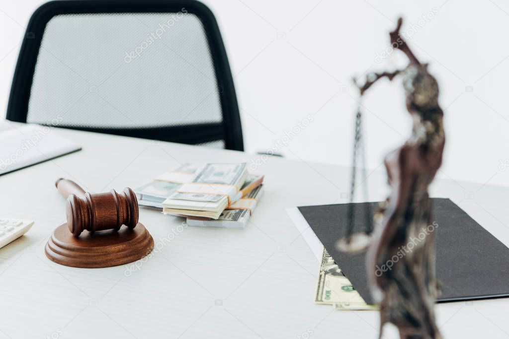 selective focus of money near gavel of judge and statuette of justice 