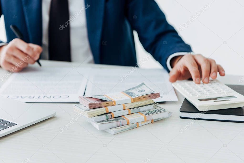 cropped view of businessman using calculator near bribe and contract 