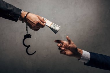 Kırpılmış Görünüm adam kelepçeler gri üzerinde iş ortağı rüşvet veren 