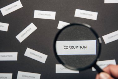 gri üzerinde yolsuzluk mektupları ile kağıt yakın insan tutma Büyüteç seçici odak 