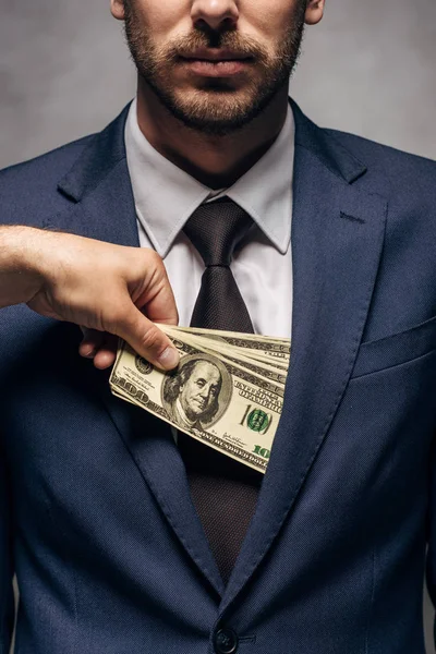 灰色のビジネスパートナーのポケットにお金を入れて男のトリミングビュー — ストック写真