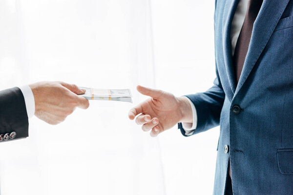 cropped view of man giving cash to business partner on white