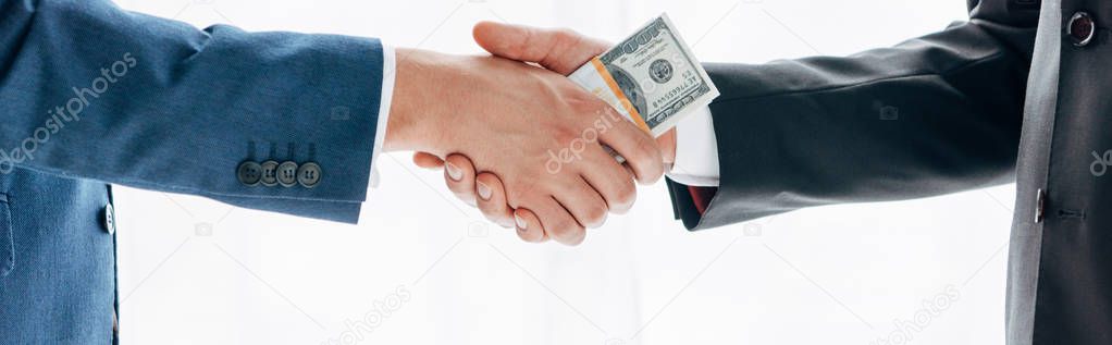 panoramic shot of man giving bribe to business partner and shaking hands isolated on white 