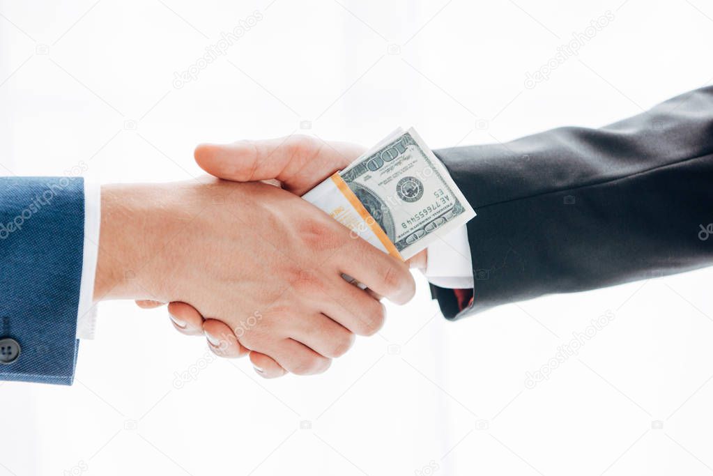 cropped view of man giving bribe to business partner while shaking hands isolated on white