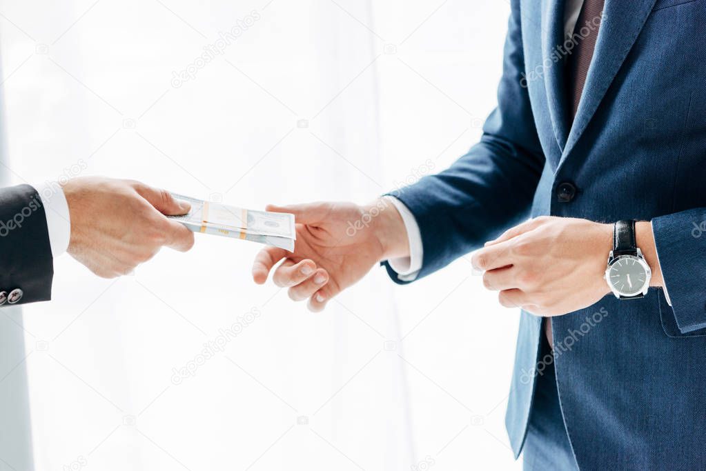 cropped view of businessman giving bribe to business partner on white