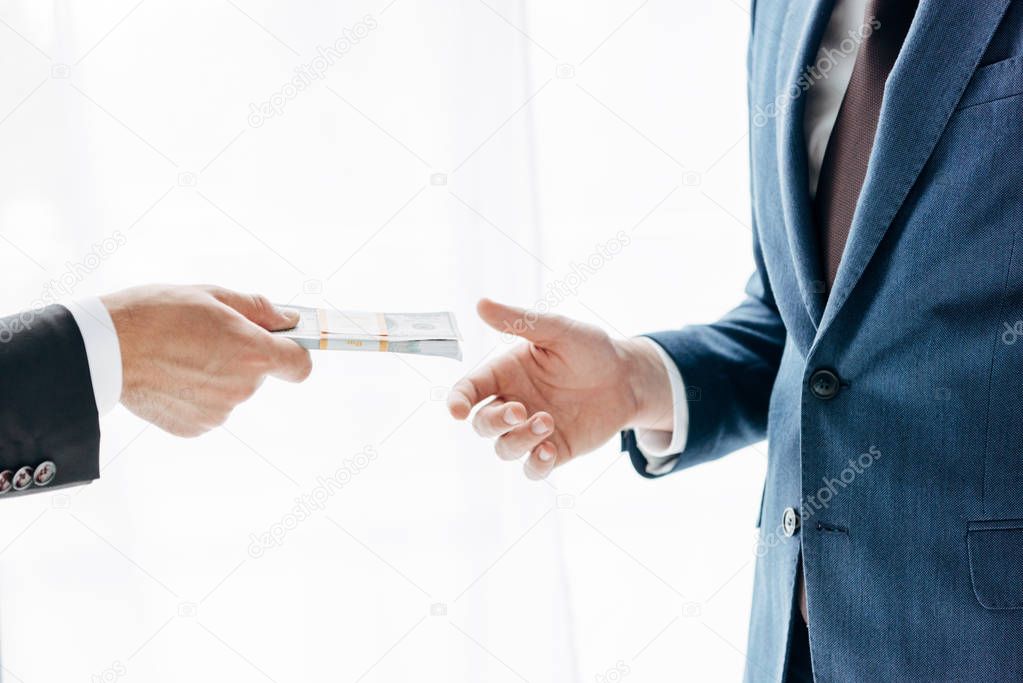 cropped view of man giving cash to business partner on white