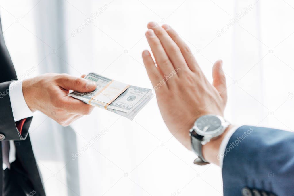 cropped view of man giving bribe to business partner gesturing on white