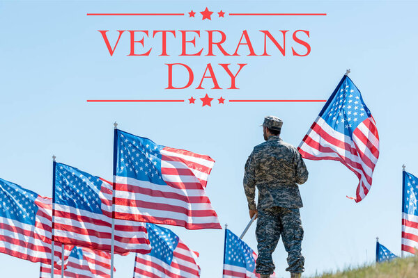 человек в военной форме и кепке, стоящий и держащий американский флаг с иллюстрацией Дня ветеранов
