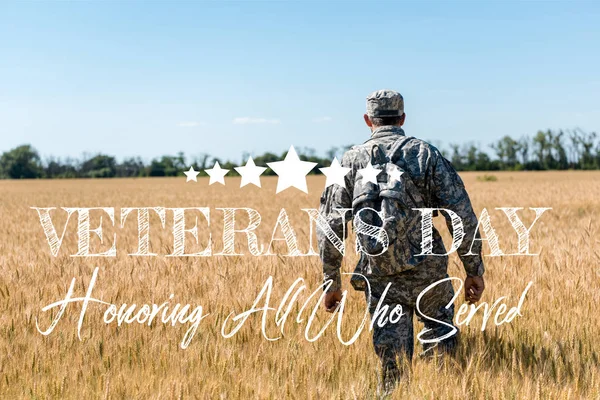 士兵在军装与背包走在田间与金小麦与退伍军人日 荣誉所有谁服务插图 — 图库照片