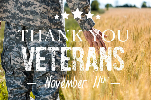 selective focus of soldier touching wheat in golden field with thank you veterans illustration