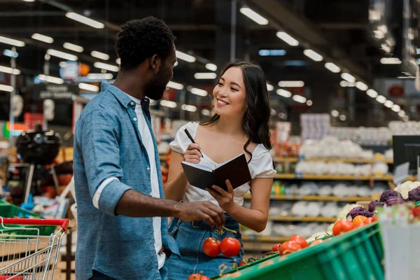 Afro Amerikai Férfi Gazdaság Friss Paradicsom Néztem Boldog Ázsiai Notebook — Stock Fotó