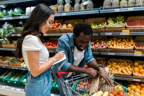 Lycklig Afrikansk Amerikansk Man Tittar Kundvagn Med Livsmedel Nära Glad — Stockfoto