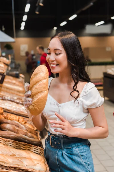 Happy Asian Woman Smiling While Smelling Bread Supermarket — Stock Photo, Image