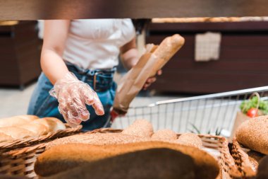 süpermarkette ekmek yakınında eldiven genç kadının kırpılmış görünümü 