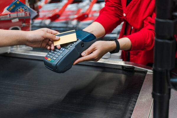 cropped view of customer paying by credit card near cashier in supermarket 