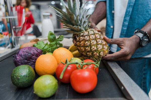 cropped view of african american man standing near supermarket counter near groceries 