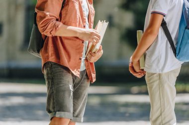 okul bahçesinde dururken kitap tutan iki okul çocuğunun kısmi görünümü