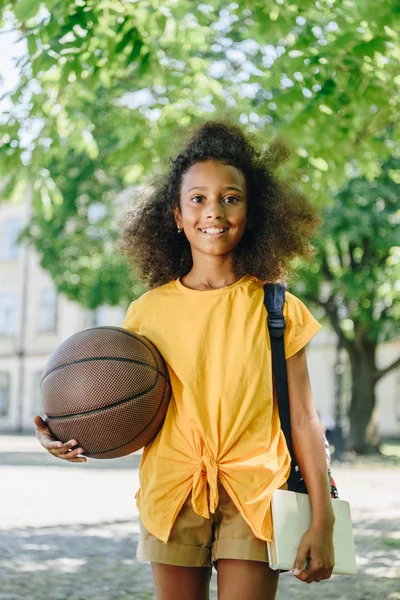 Glad Afrikansk Amerikansk Schoolgirl Håller Bollen Och Ler Mot Kameran — Stockfoto