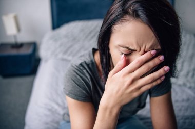 depresif kadın evde yatakta oturan, ağlama ve elleriyle yüz kaplama