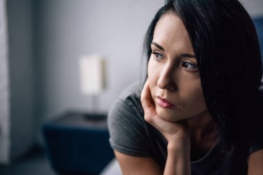selective focus of beautiful depressed woman looking away at home clipart