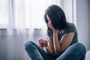 depressed woman with whiskey glass crying at home clipart