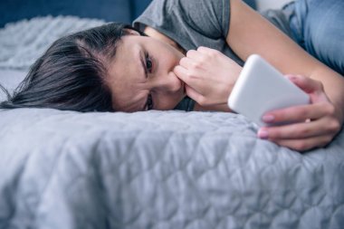 yatak odasında akıllı telefon kullanarak yatakta yalnız üzgün kadın