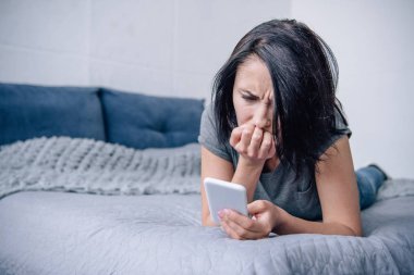 yatak odasında akıllı telefon kullanarak yatakta yalnız depresif kadın