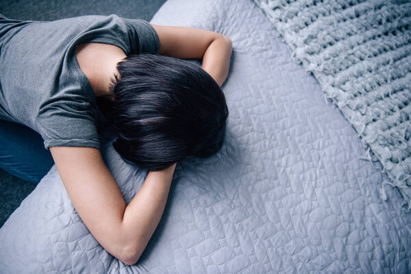 вид сверху на депрессивную женщину лежащую на кровати дома с копировальным пространством
