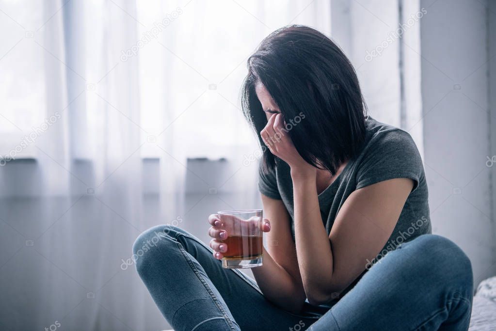 depressed woman with whiskey glass crying at home