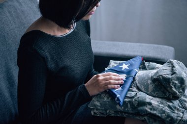 askeri giyim ve evde amerikan bayrağı foded ile kanepede kadının kırpılmış görünümü