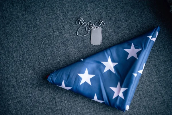 タグ犬と自宅のソファに折り畳まれたアメリカの旗 — ストック写真