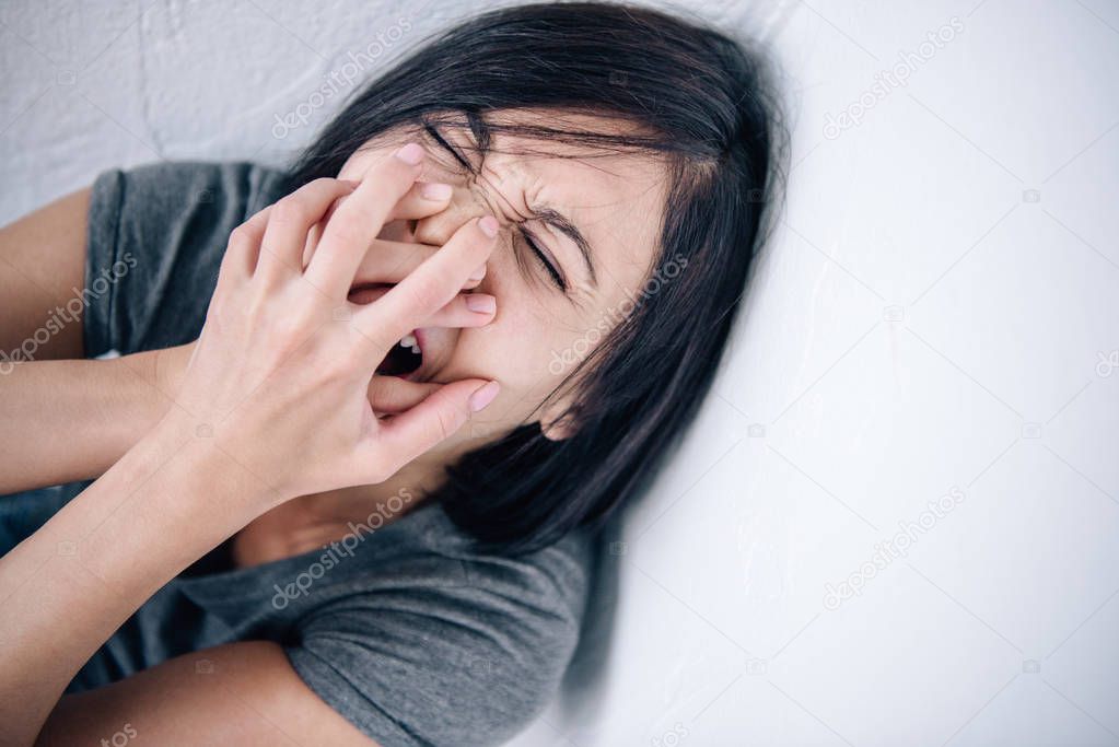 depressed brunette woman covering mouth and screaming at home